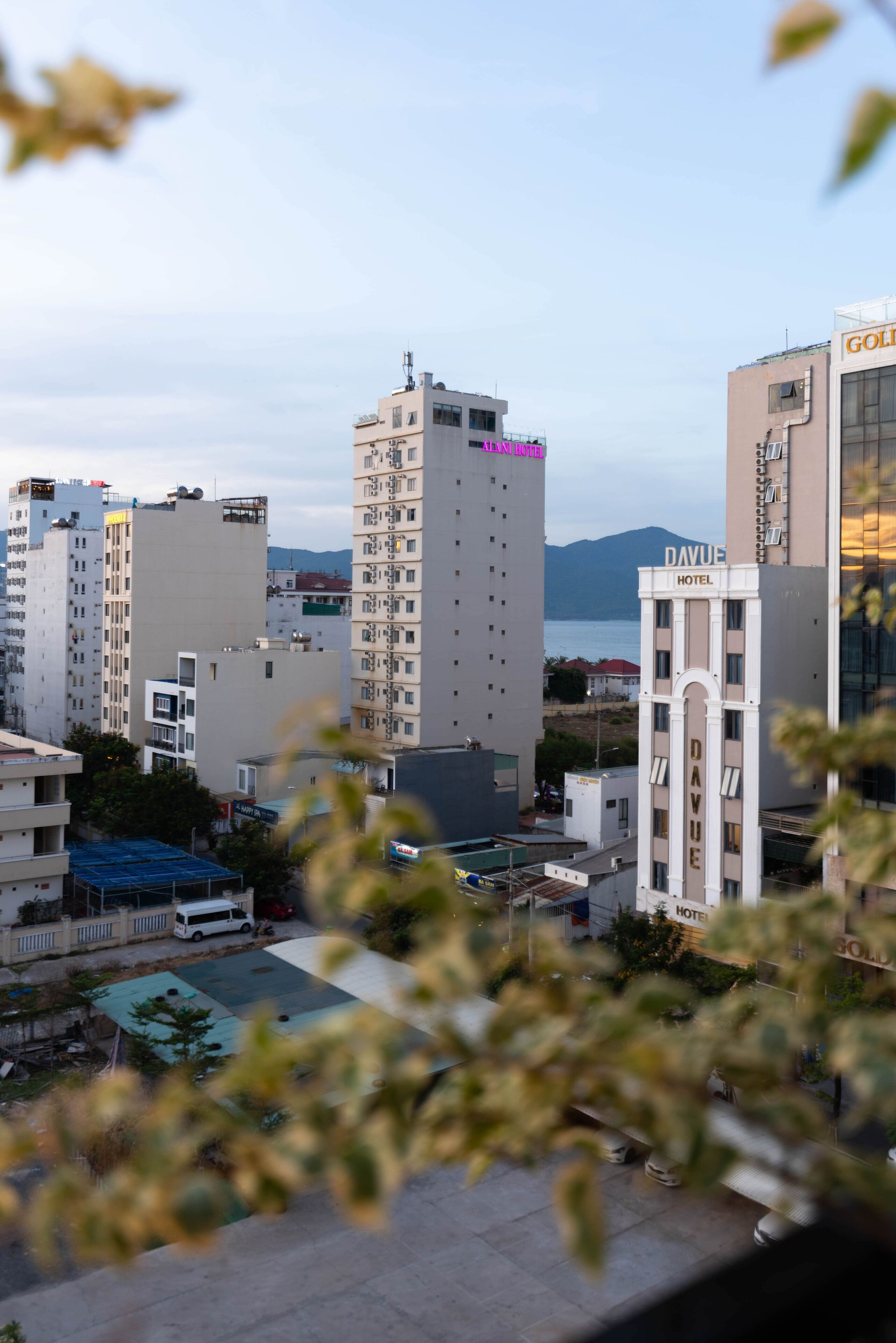 A hotel with multiple floors, a prominent 'HOTEL' sign, and a view of the sea in the background.