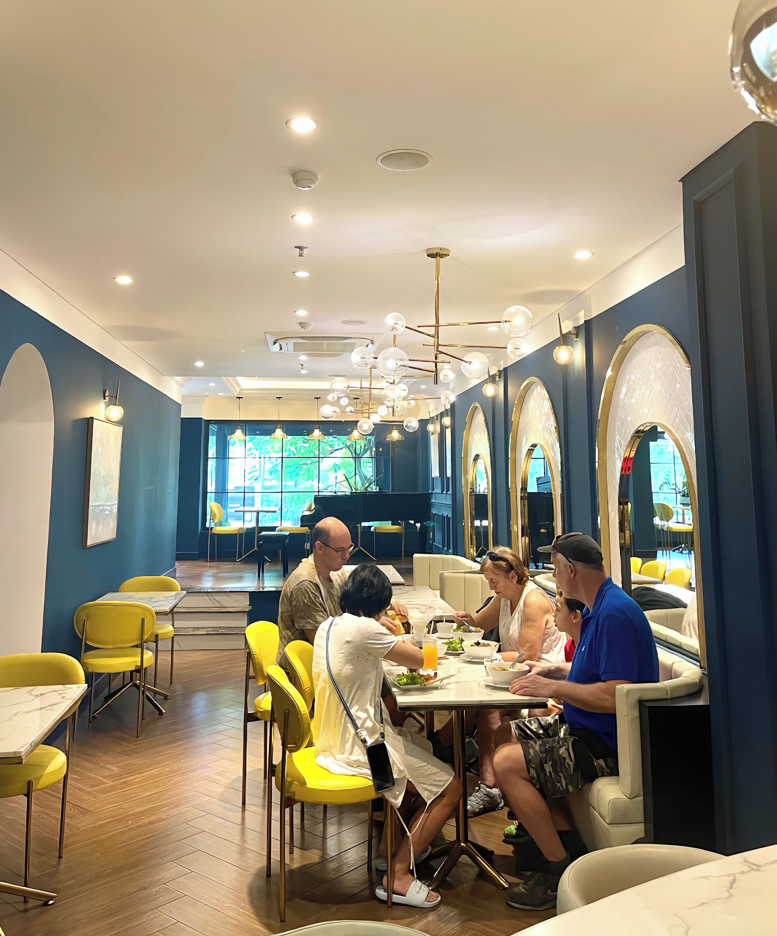 A restaurant with yellow chairs, marble tables, and a blue wall.