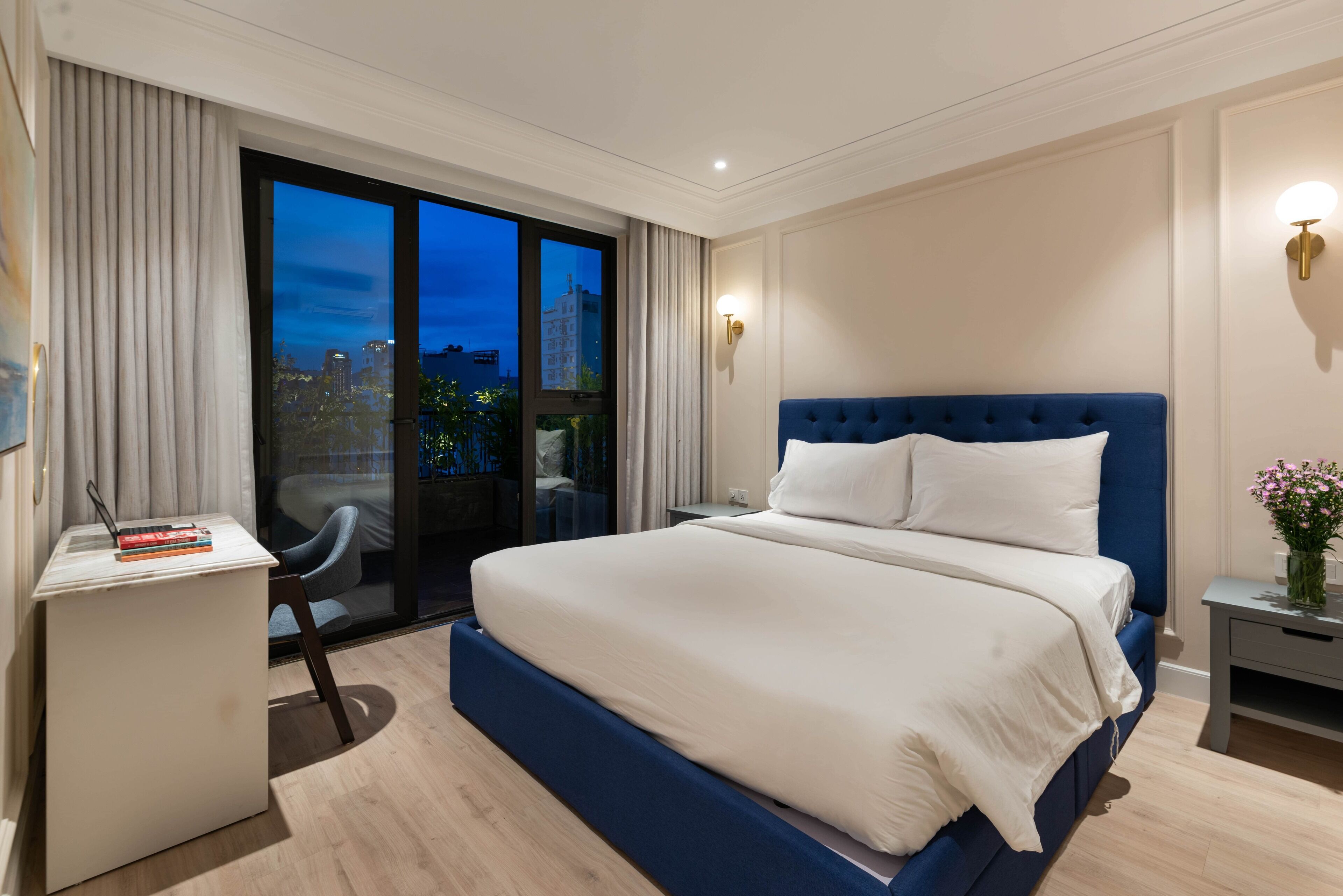 A hotel room with a large bed, a desk, and a chair.