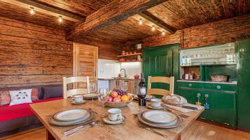 Un intérieur en bois avec une table à manger pour quatre personnes, un coin cuisine et un canapé rouge.