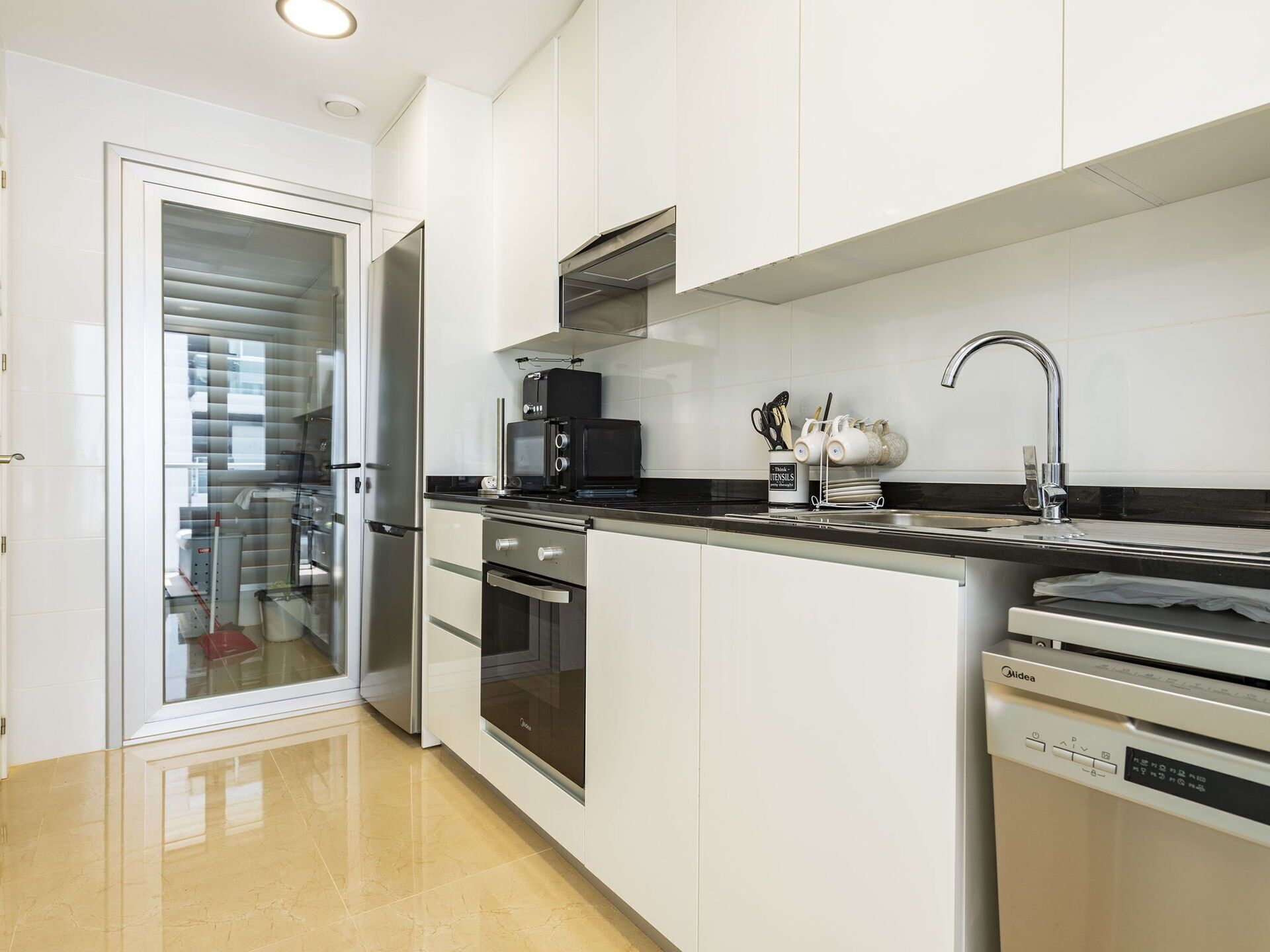 A modern kitchen with stainless steel appliances, a black countertop, and a dishwasher.