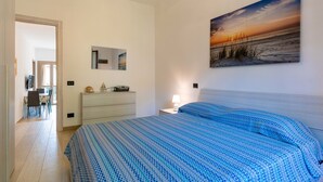 Ein Schlafzimmer mit Bett, Schminktisch, Nachttisch, einem Gemälde und einem Essbereich mit Stühlen und Tisch.