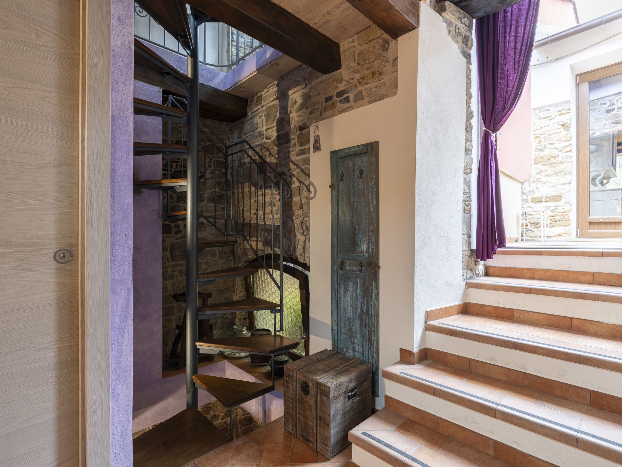 Un escalier avec des marches en bois, un mur en pierre et une porte bleue.