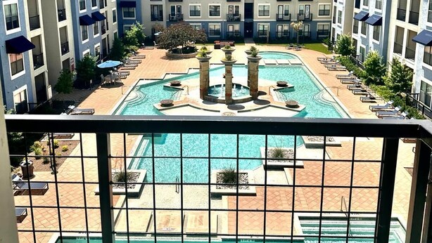 A hotel courtyard with a central pool, lounge chairs, and a multi-story building with balconies. - Apartment in the Heart of Frisco (Frisco)