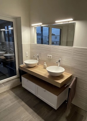 A modern bathroom with two sinks, a large mirror, and a towel rack. - Holiday Home Sailorskoje (Kappeln)