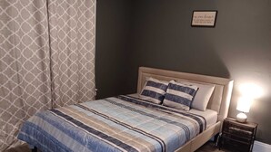 Une chambre à coucher avec un lit, une lampe de chevet, un tapis et un tableau accroché au mur.