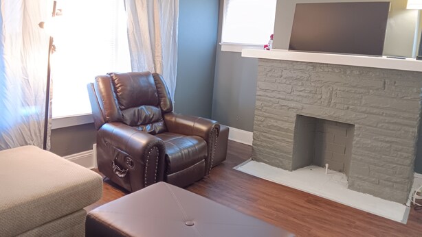 Un salon comprenant un fauteuil en cuir, un canapé, une cheminée et un téléviseur à écran plat fixé au-dessus de la cheminée.