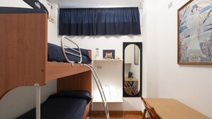 Een studentenkamer met stapelbedden, een bureau, een stoel, een spiegel en een schilderij aan de muur.