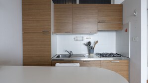 Een moderne keuken met houten kastjes, een roestvrijstalen spoelbak en een gasfornuis.