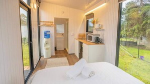A bedroom with a bed, a bathroom, and a kitchenette. - Sparkling Tiny House by Tiny Away (Windeyer)