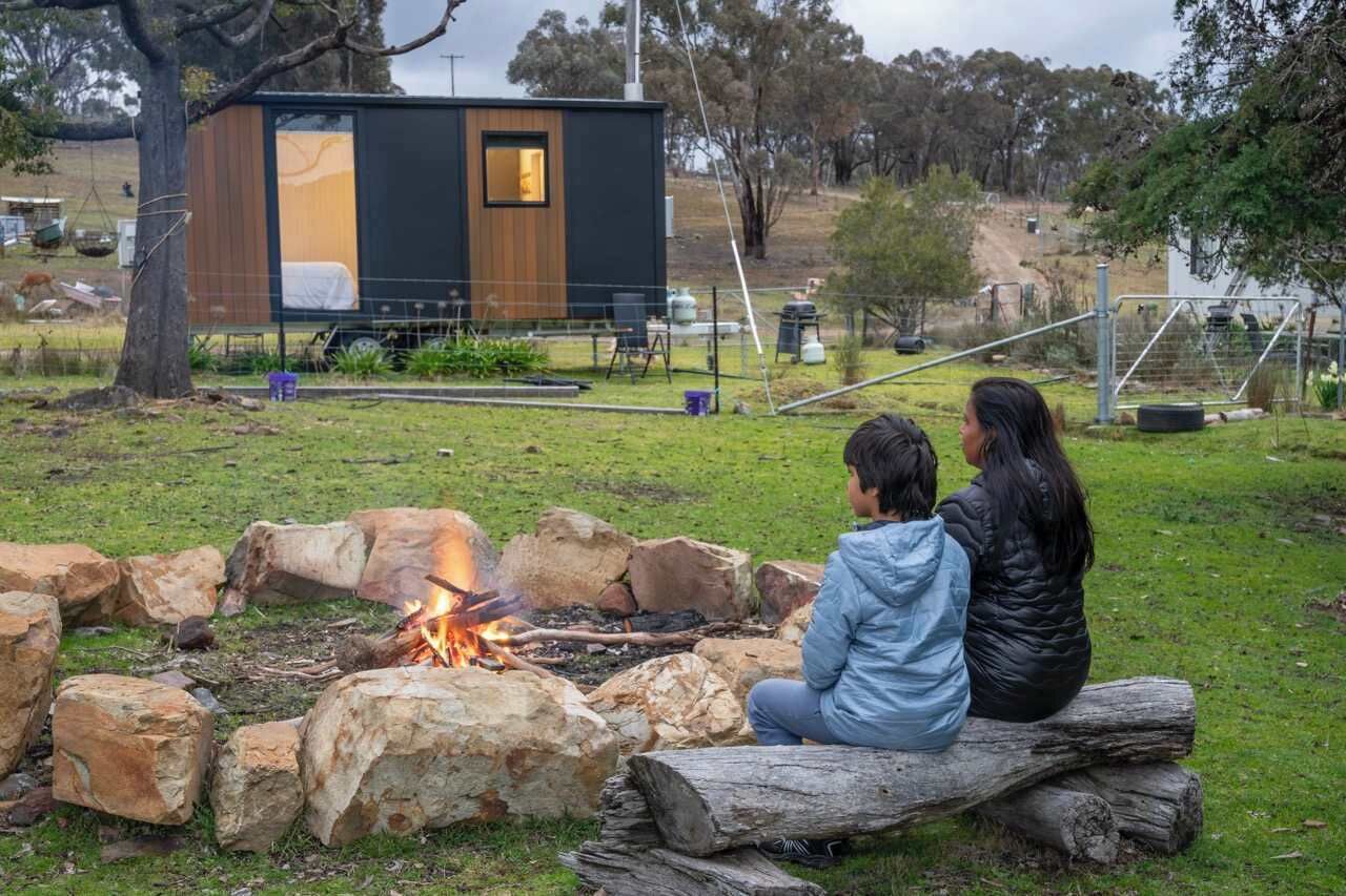 Una cabana moderna amb una zona de foc, una petita terrassa i un pati tancat.
