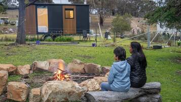 Una cabana moderna amb una zona de foc, una petita terrassa i un pati tancat.