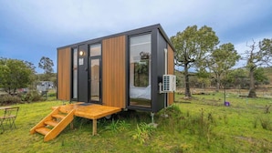A modern, compact cabin with a wooden deck, large windows, and an air conditioning unit. - Sparkling Tiny House by Tiny Away (Windeyer)