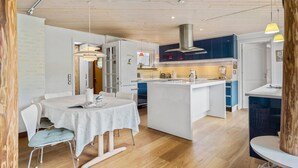 A modern kitchen with a central island, white cabinetry, and pendant lighting. - Cozy home in Græsted with sauna (Græsted)