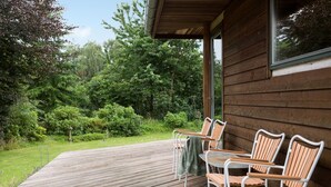 A wooden deck with outdoor seating, surrounded by lush greenery and trees. - Cozy home in Græsted with sauna (Græsted)