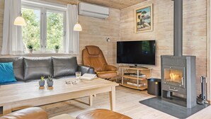 Un salon chaleureux avec un canapé en cuir, une table basse en bois, un téléviseur et un poêle à bois.