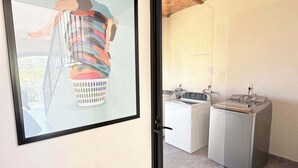 Un intérieur moderne agrémenté d’une œuvre d’art encadrée, d’un lave-linge et d’une cuisinière.