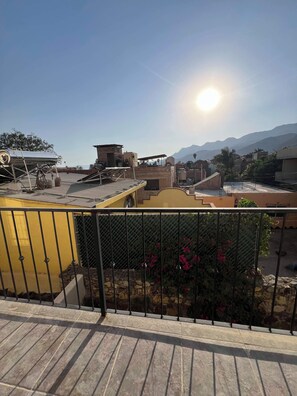 Una terraza con cerramiento metálico, una estructura amarilla y vistas a montañas distantes.