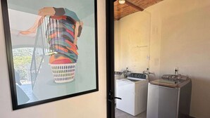 A modern kitchen with a stove, washing machine, and a large framed artwork on the wall. - Tranquil Studio Suite with Outdoor Salt Water Pool (Ajijic)
