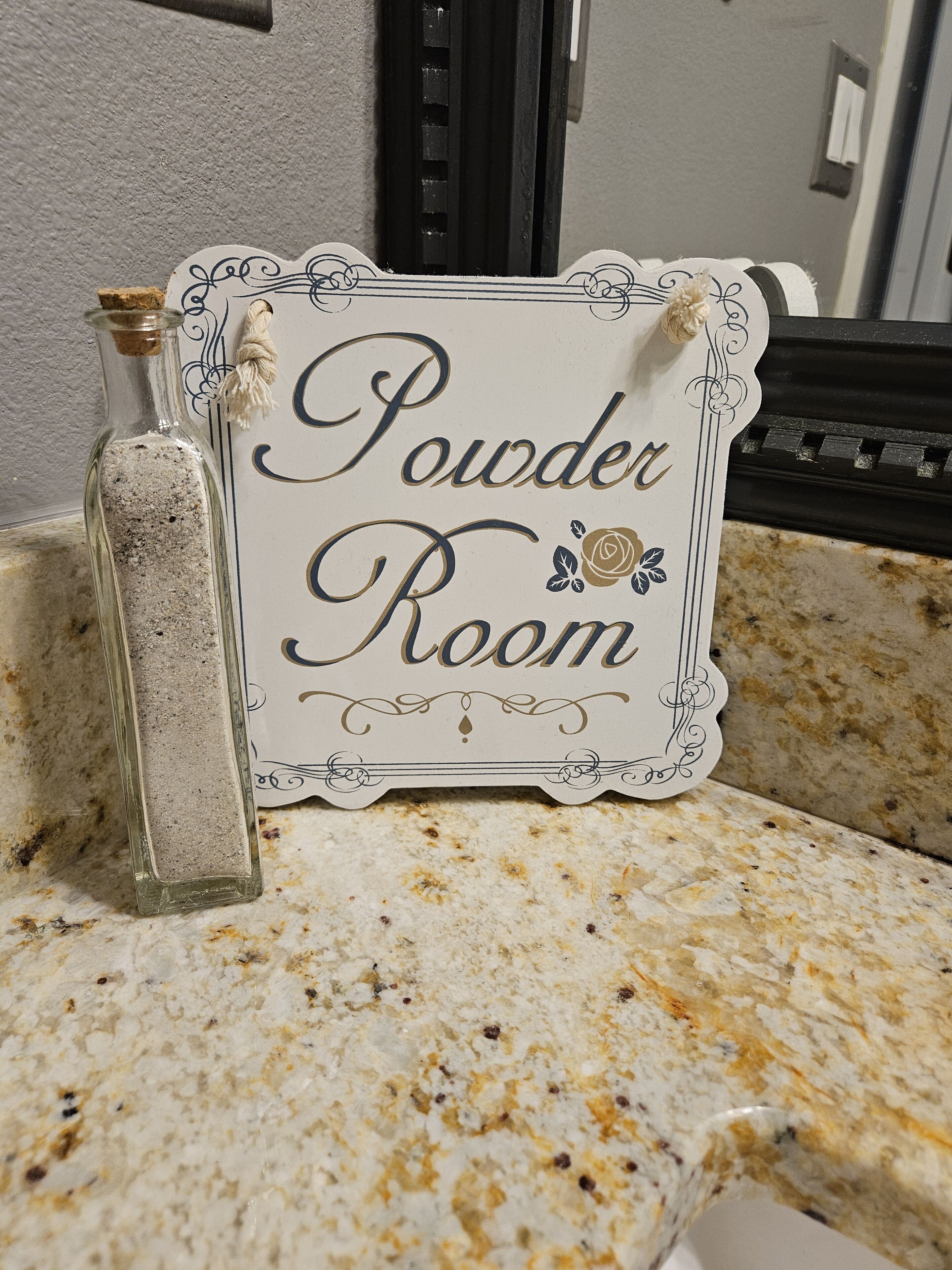 Un cartello con la scritta 'Powder Room' su un bancone.
