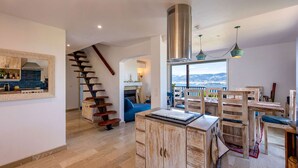 Una cocina amplia con estufa moderna, gabinetes de madera y un comedor con un gran ventanal con vistas panorámicas.
