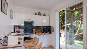 Una cocina moderna con armarios blancos, un salpicadero de azulejos azules y un comedor con sillas de mimbre.