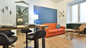 Una sala moderna con comedor, una pared de acento azul y un ventanal grande.