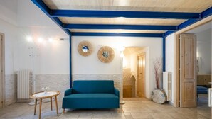 Een kamer met een blauwgroene bank, een ronde tafel en een spiegel aan de muur.