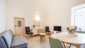 Een moderne kamer met een bank, stoelen, een tafel, een kast en een deur.