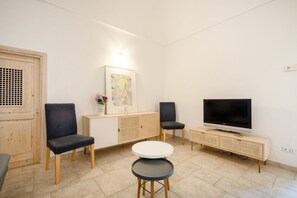 Una sala de estar moderna con televisor, dos sillones, una mesita y un mueble aparador.