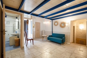 Una habitación con techo de madera, un sofá azul, una mesita y una silla.
