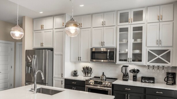 A modern kitchen with white cabinets, stainless steel appliances, and pendant lighting. - Reluxme | Uptown 3BR w/ King Beds & Spa Access (Charlotte)