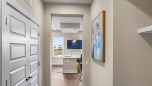 A hallway leading to a bathroom with a sink and a framed artwork on the wall. - Reluxme | Uptown 3BR w/ King Beds & Spa Access (Charlotte)