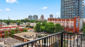 A cityscape with a mix of modern and older buildings, a clear sky, and a view of a busy street with cars. - Reluxme | Uptown 3BR w/ King Beds & Spa Access (Charlotte)
