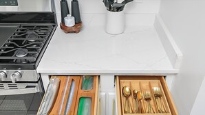 A kitchen with a stove, a drawer with utensils, and a marble countertop. - Family & Pet Friendly Modern Townhouse (Alabaster)