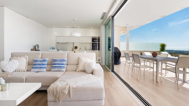 Een moderne woonkamer met een bank, salontafel en een balkon met zitplaatsen buiten.