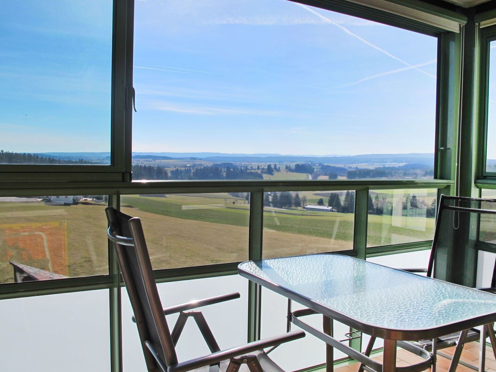 A room with a large window offering a view of a rural landscape.