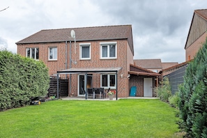 A two-story brick house with a patio, a garage, and a well-maintained lawn. - Holiday Home 'Ferienhaus Heide' with Private Terrace and Wi-Fi (Bad Fallingbostel)