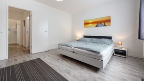 A modern bedroom with a bed, bedside table, and a painting on the wall.