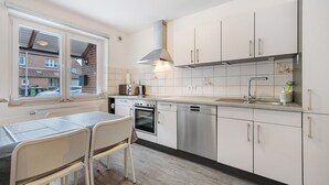 A modern kitchen with white cabinets, stainless steel appliances, and a window overlooking a residential area.