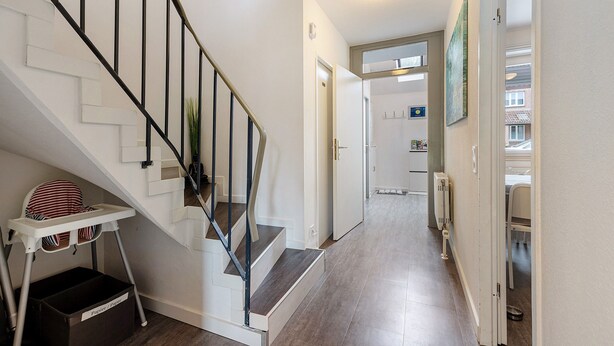 A staircase with a metal railing, a white wall, and a door leading to another room.