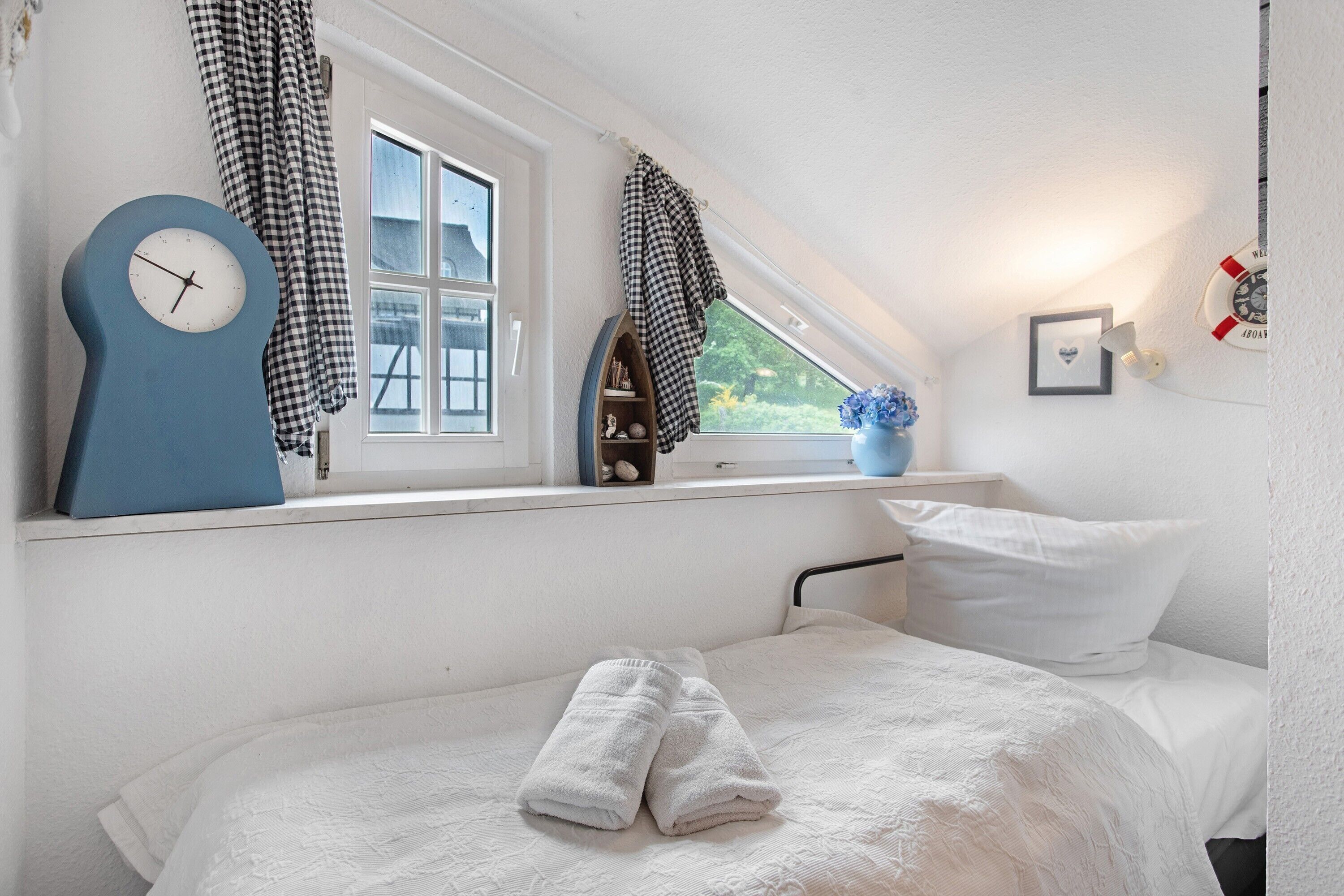 Un dormitorio con cama, ventana, reloj y vistas al exterior.