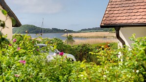 A house with a tiled roof, a view of a lake, and surrounding greenery. - Apartment 'Fewo Yachthafenblick Nr 5' with Sea View, Private Terrace and Wi-Fi (Ostseebad Sellin)