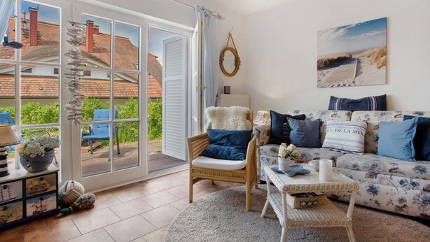 A living room with a sofa, chair, and a view of the outside. - Apartment 'Fewo Yachthafenblick Nr 5' with Sea View, Private Terrace and Wi-Fi (Ostseebad Sellin)