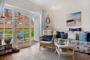 Una sala de estar con sofá, sillón y vistas al exterior.
