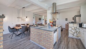 Une cuisine moderne dotée d’un îlot central, d’un coin repas avec une table et des chaises en bois, et d’un revêtement mural imitant la pierre.