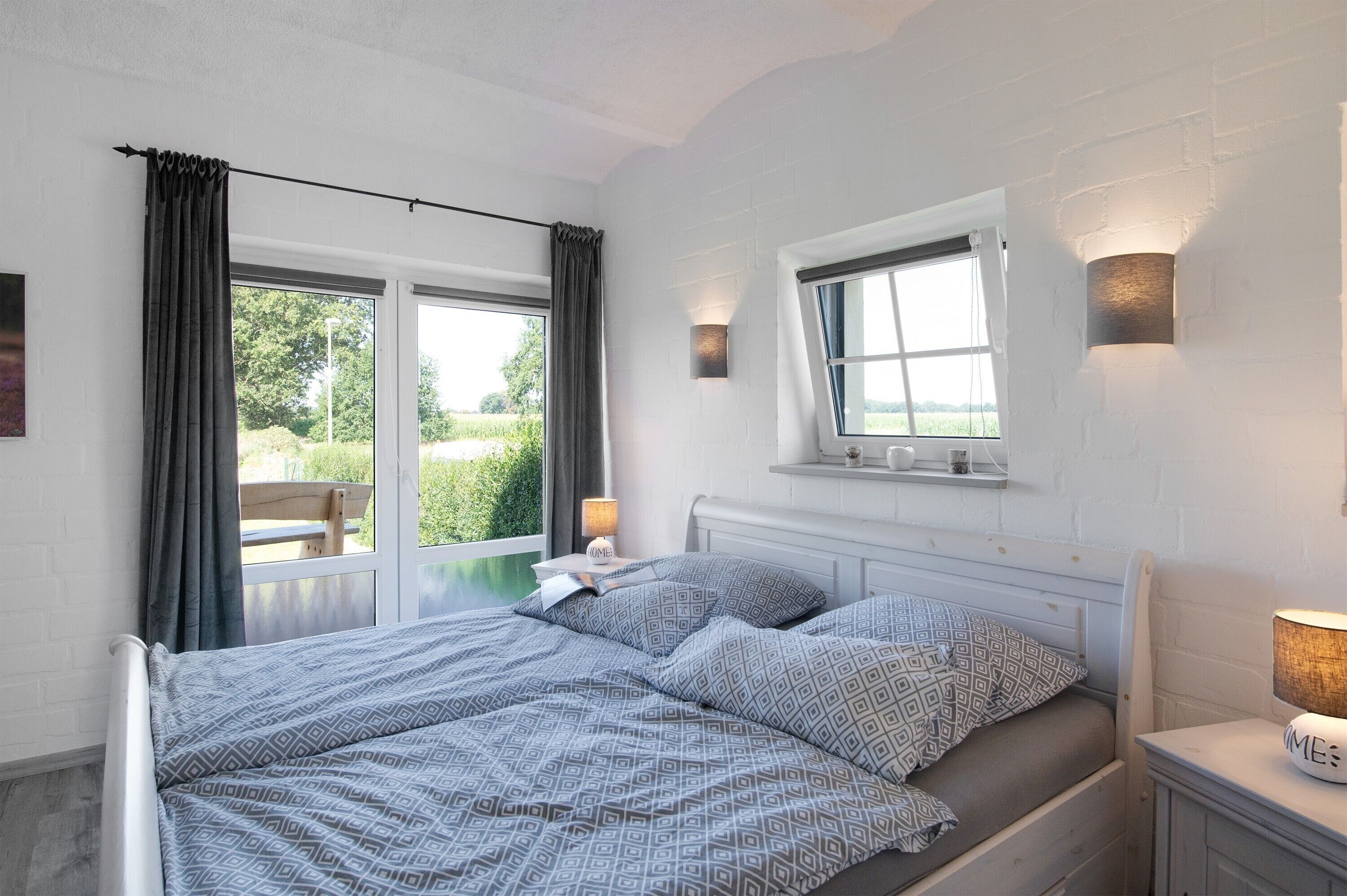 A bedroom with a bed, a window, a nightstand, and a lamp.