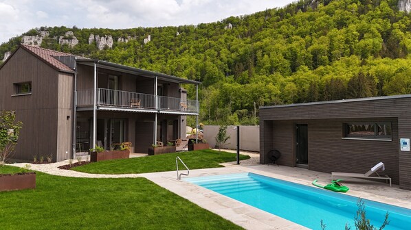 Un bâtiment à deux étages doté d’un balcon, d’une piscine et d’une petite construction adjacente.
