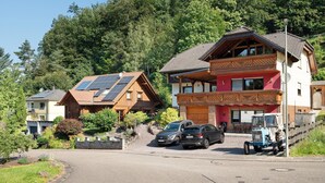 Et boligområde med huse, en indkørsel, parkerede biler og en traktor.