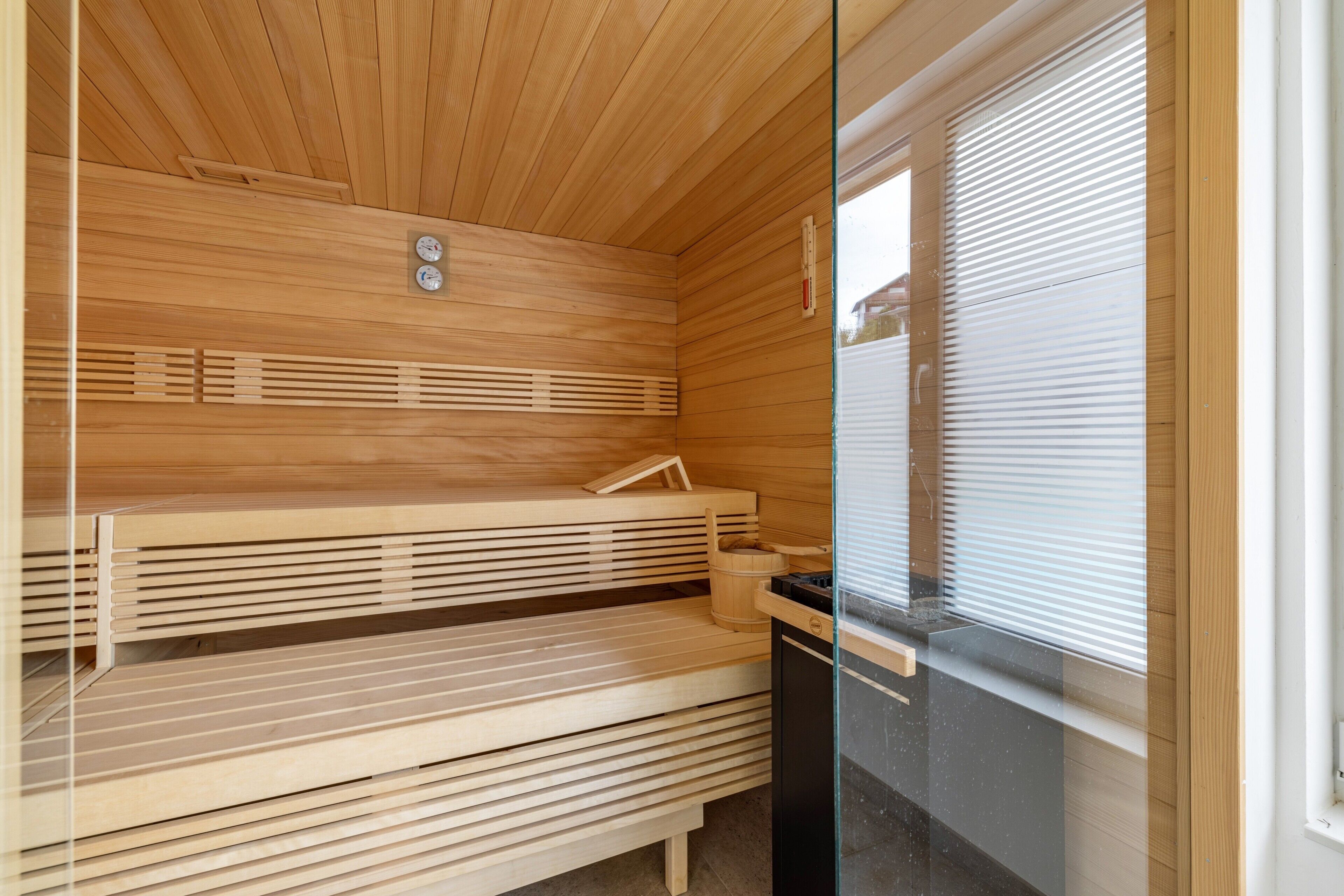 Een sauna met houten banken, een houten plafond en een raam met zonwering.